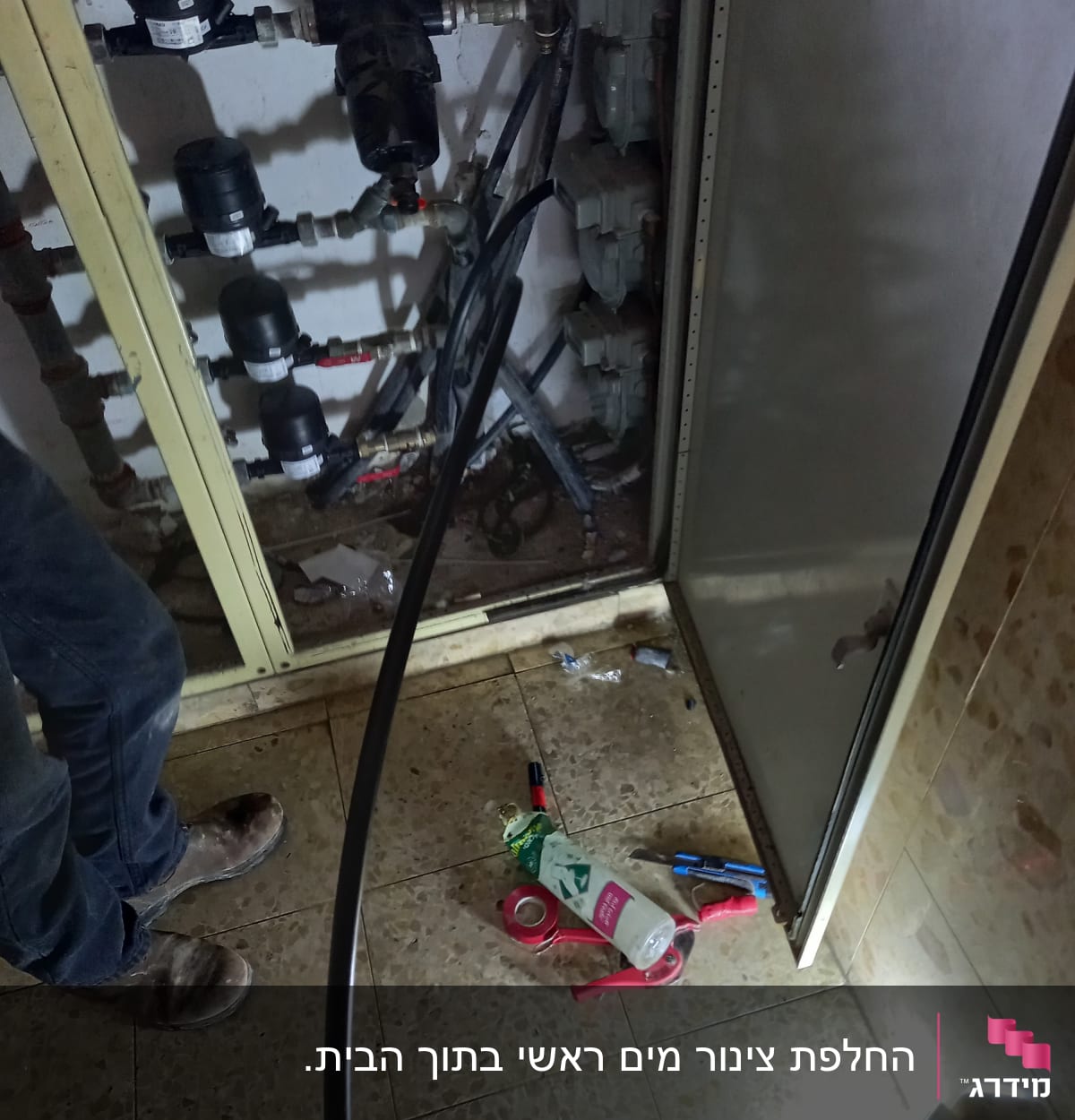 ארון צנרת עם כלים וחומרים על הרצפה